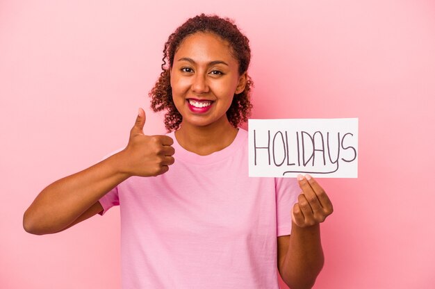 Young African American woman holding a Holidays placard isolated on pink background