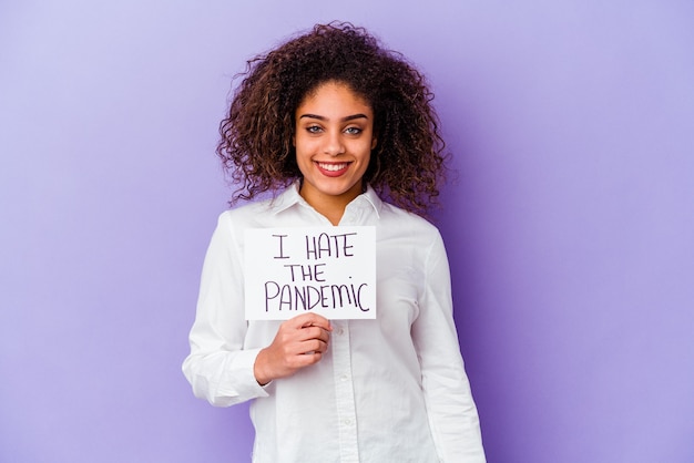 Young African American woman holding I hate pandemic placard isolated on purple wall happy, smiling and cheerful.