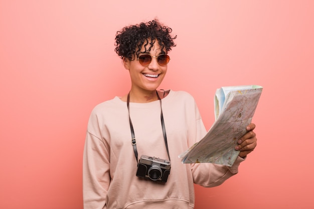 Giovane donna afroamericana che giudica una mappa felice, sorridente e allegra