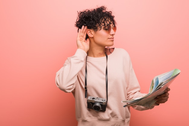 Young african american woman holding a map trying to listening a gossip.