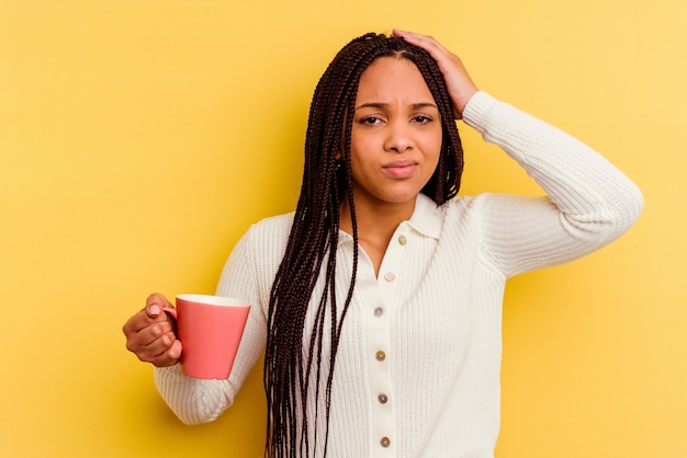 Young african american woman holding a mug isolated being shocked, she has remembered important meeting.