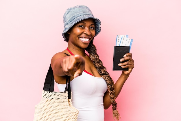 분홍색 배경에 격리된 여권을 들고 있는 젊은 흑인 여성