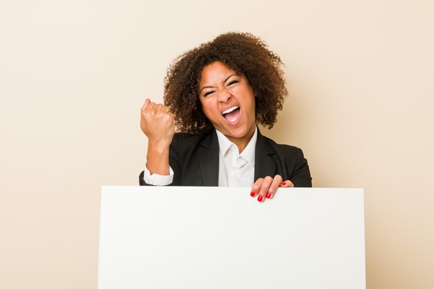 Young african american woman holding a placard cheering carefree and excited. Victory concept.