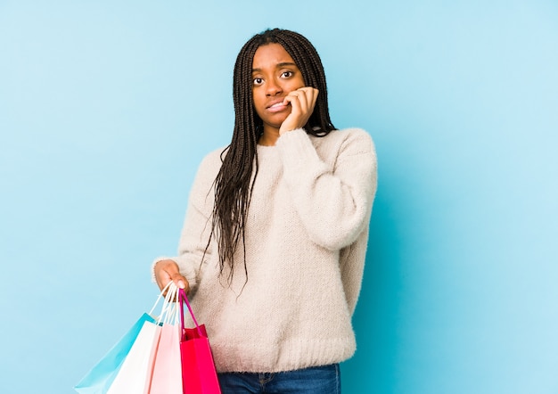 ショッピングバッグを持っている若いアフリカ系アメリカ人の女性は、神経質で非常に不安な、噛む爪を孤立させました。