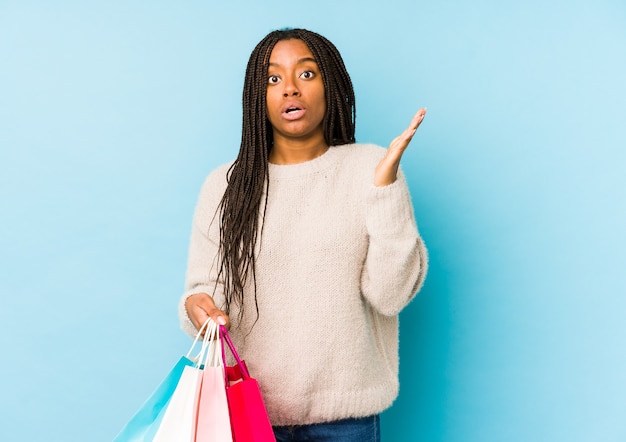 Young african american woman holding a shopping bag isolated surprised and shocked.