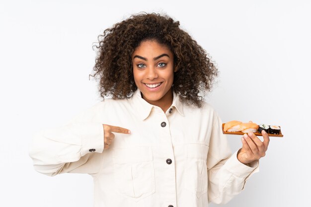 驚きの表情で白で隔離される寿司を保持している若いアフリカ系アメリカ人女性