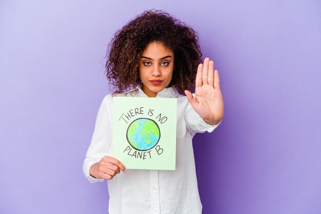 Foto giovane donna afroamericana in possesso di un cartello non c'è nessun pianeta b isolato in piedi con la mano tesa che mostra il segnale di stop, impedendoti.