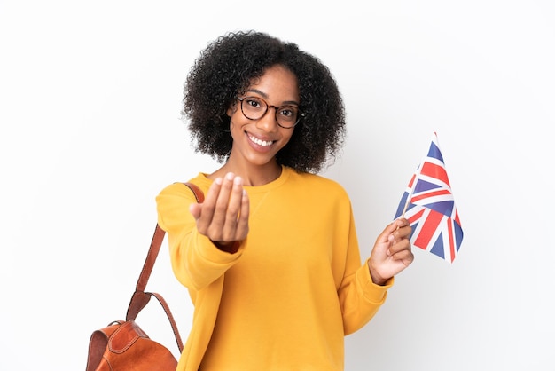 Young African American woman holding an United Kingdom flag isolated on white background inviting to come with hand Happy that you came