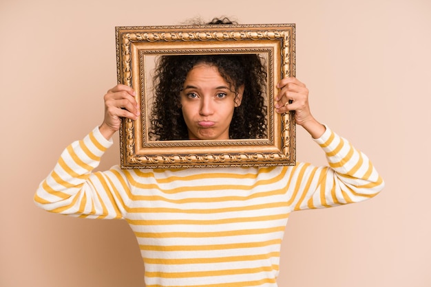 Foto giovane donna afroamericana che tiene una cornice d'epoca isolata