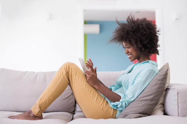 Young african american woman at home relaxing in her luxury lliving room reading a digital tablet PC surf internet and work