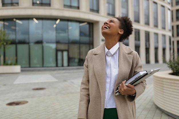 Young african american woman hr manager laughs with a laptop in her hands on the background of a