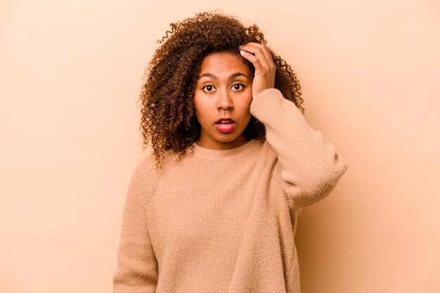 Young African American woman isolated on beige background being shocked she has remembered important meeting