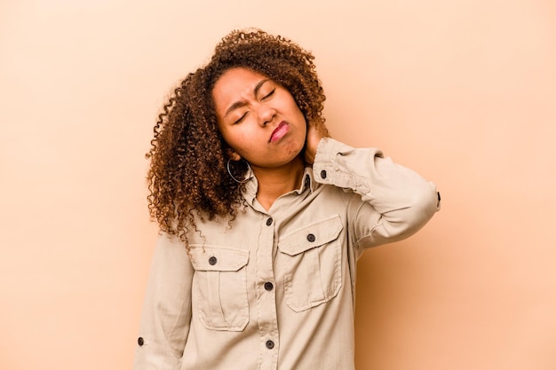 Photo young african american woman isolated on beige background tired and very sleepy keeping hand on head