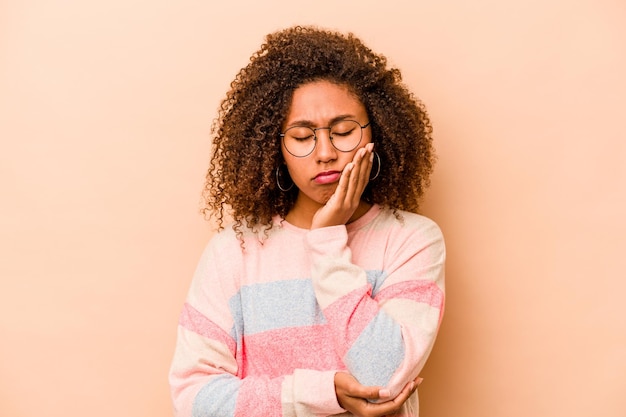 Young African American woman isolated on beige background who is bored fatigued and need a relax day