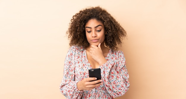 Young African American woman isolated on beige thinking and sending a message