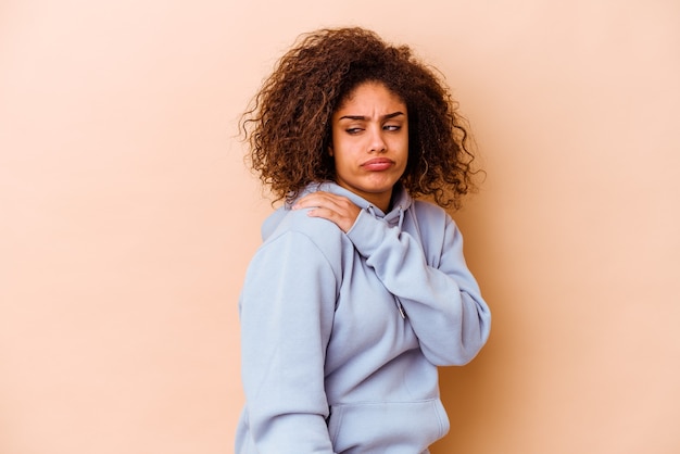 Young african american woman isolated on beige wall having a shoulder pain.