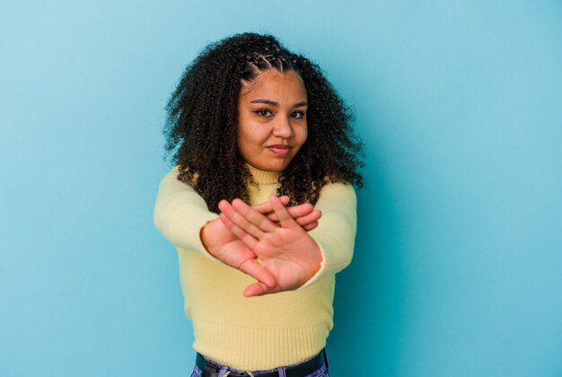 拒否ジェスチャーをしている青い背景で隔離の若いアフリカ系アメリカ人女性