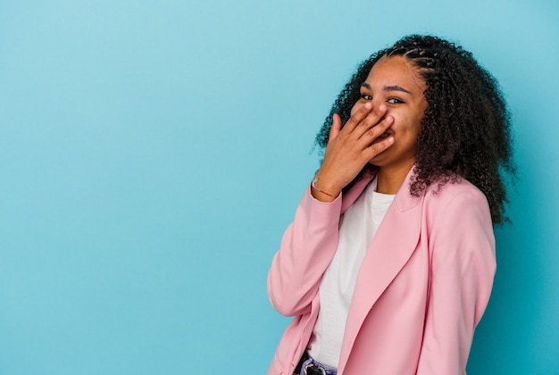 Young african american woman isolated on blue background laughing happy, carefree, natural emotion.