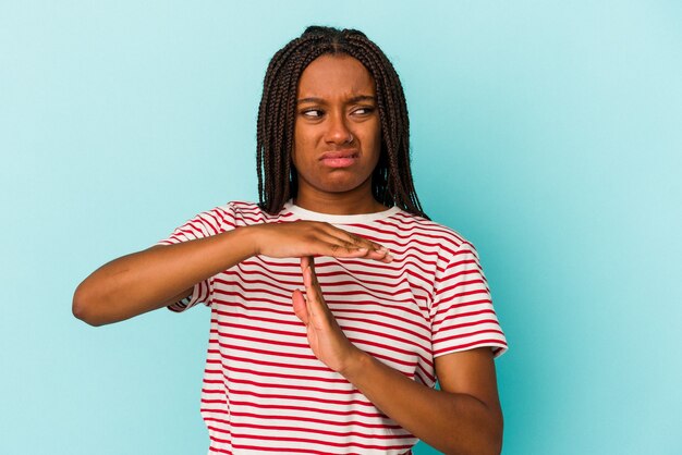 Young african american woman isolated on blue background  showing a timeout gesture.