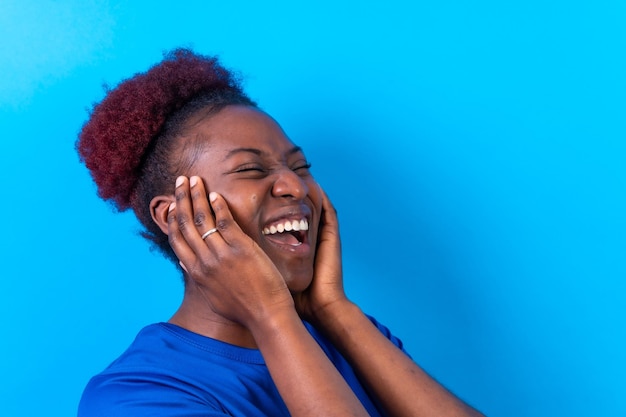 Young african american woman isolated on a blue background smiling and laughing studio shoot