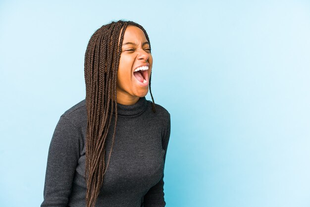 Young african american woman isolated on blue shouting towards a copy space