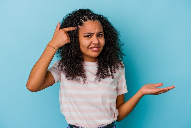 Young african american woman isolated on blue wall showing a disappointment gesture with forefinger.