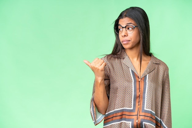 Photo young african american woman over isolated chroma key background unhappy and pointing to the side