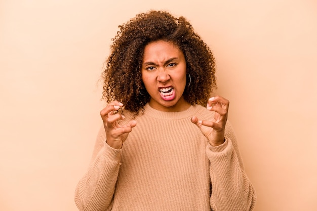 사진 베이지색 배경에 고립되어 분노로 비명을 지르는 젊은 아프리카계 미국인 여성