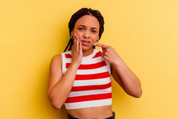 Фото Молодая афро-американская женщина изолирована на желтом фоне с сильной зубной болью, молярной болью.