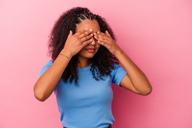 Young african american woman isolated on pink background afraid covering eyes with hands.