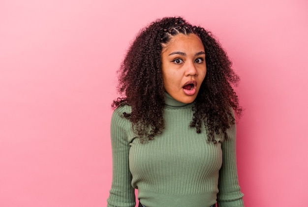 Young african american woman isolated on pink background being shocked because of something she has seen.