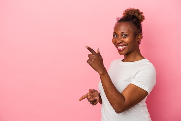 Young african american woman isolated on pink background excited pointing with forefingers away.