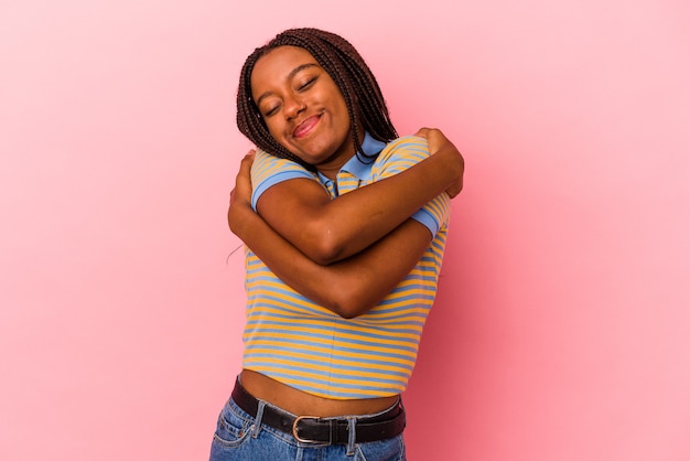 Young african american woman isolated on pink background  hugs, smiling carefree and happy.