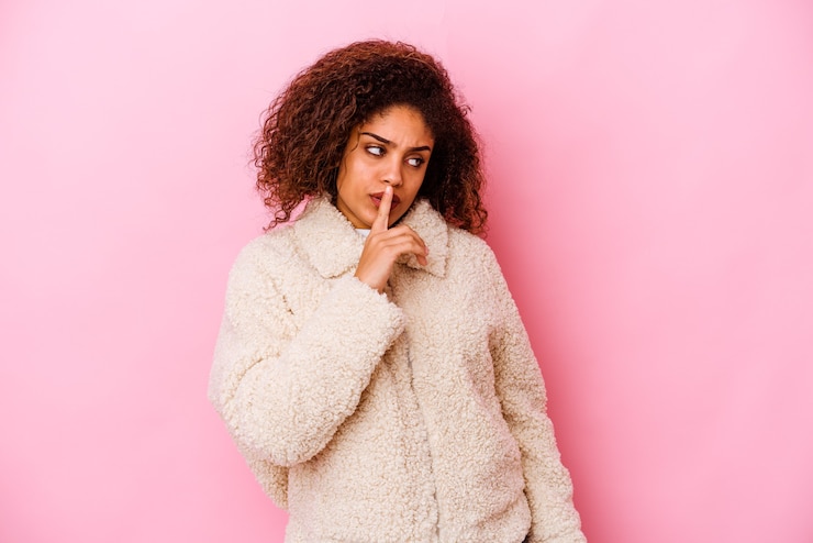 Photo young african american woman isolated on pink background keeping a secret or asking for silence.