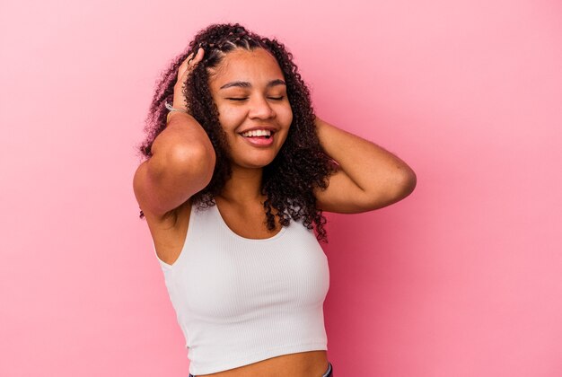 Young african american woman isolated on pink background laughs joyfully keeping hands on head. Happiness concept.