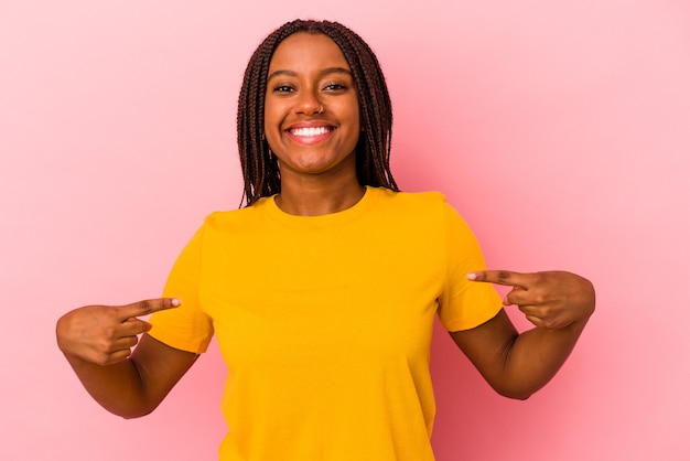 Young african american woman isolated on pink background  points down with fingers, positive feeling.