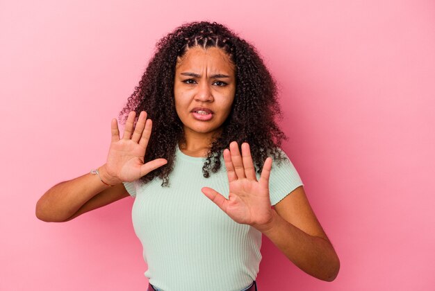 Young african american woman isolated on pink background rejecting someone showing a gesture of disgust.