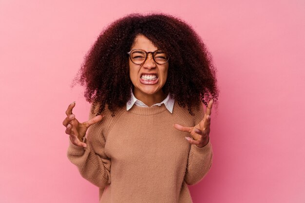 Young african american woman isolated on pink background screaming with rage.