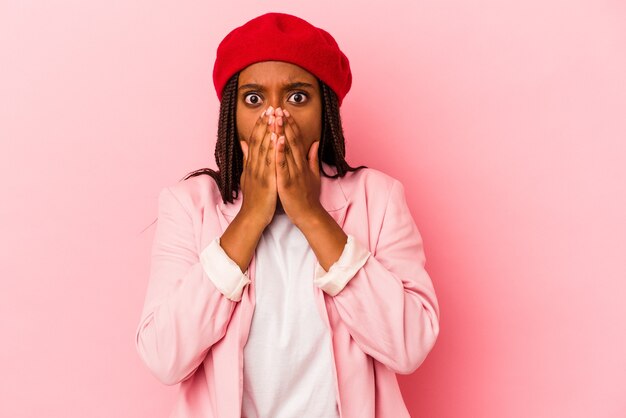 Young african american woman isolated on pink background  shocked, covering mouth with hands, anxious to discover something new.