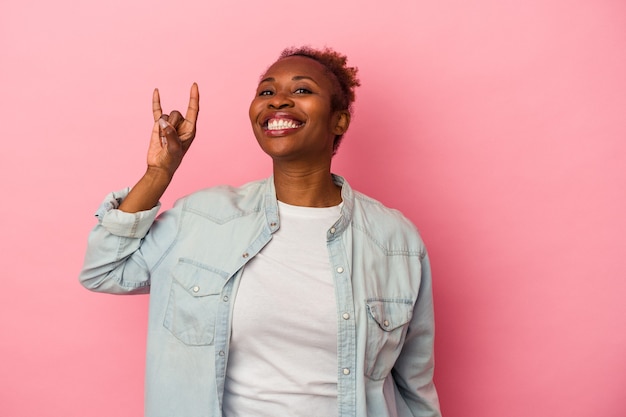 Young african american woman isolated on pink background showing a horns gesture as a revolution concept.