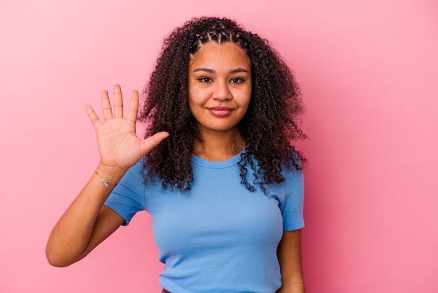 Young african american woman isolated on pink background smiling cheerful showing number five with fingers.