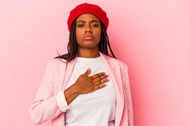 Young african american woman isolated on pink background  taking an oath, putting hand on chest.