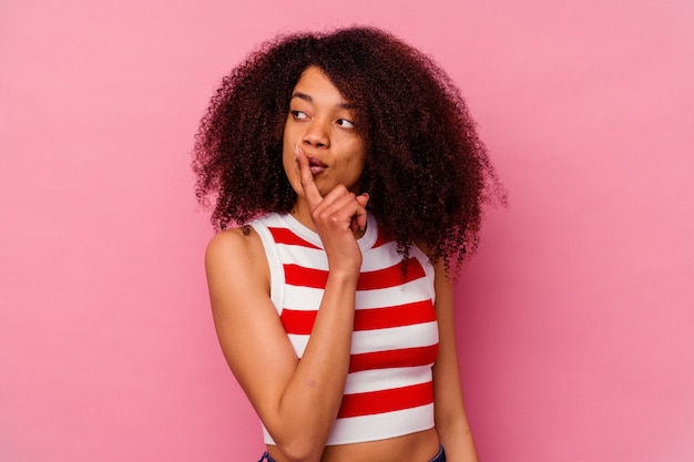 Young african american woman isolated on pink keeping a secret or asking for silence.