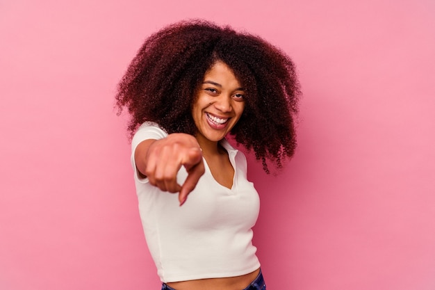 ピンクの壁に孤立した若いアフリカ系アメリカ人女性は、正面を指している陽気な笑顔。