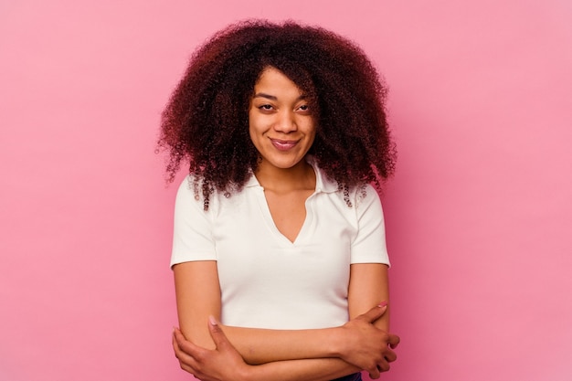 젊은 아프리카 계 미국인 여자는 자신감을 느끼고 분홍색 벽에 고립, 결정으로 팔을 교차.