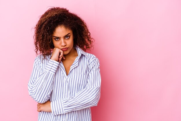 Young african american woman isolated on pink wall who feels sad and pensive, looking at copy space.