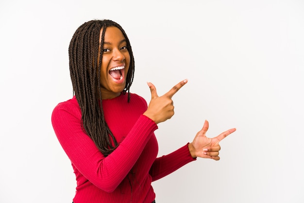 Young african american woman isolated pointing with forefingers to a copy space, expressing excitement and desire.