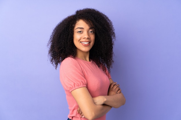 Giovane donna afroamericana isolata su viola con le braccia incrociate e guardando avanti