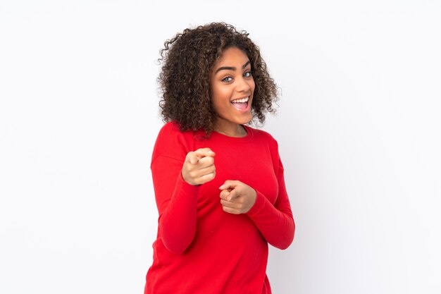 Young African American woman isolated on space surprised and pointing front