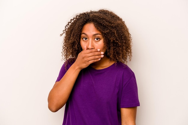 Foto giovane donna afroamericana isolata su sfondo bianco che copre la bocca con le mani che sembrano preoccupate